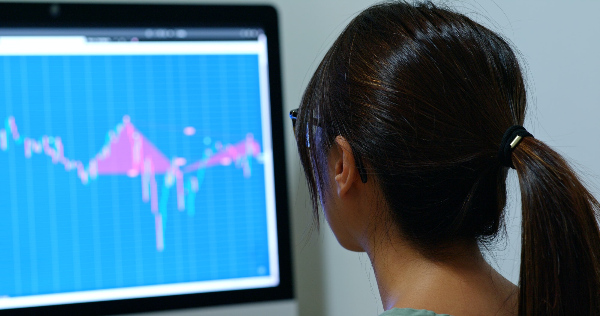 Woman look at computer screen with stock market data graph