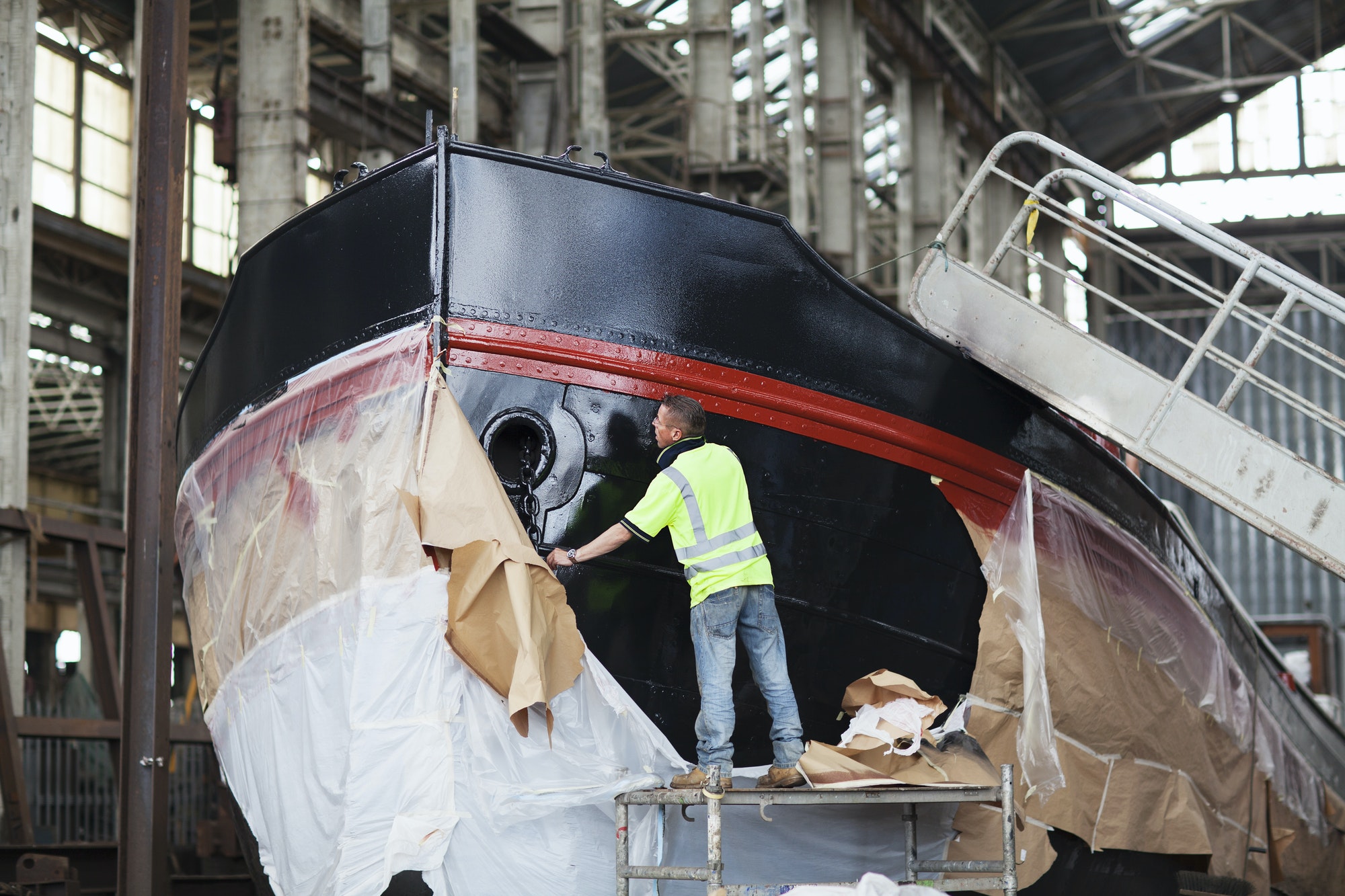 Workers unwrapping boat in shipyard