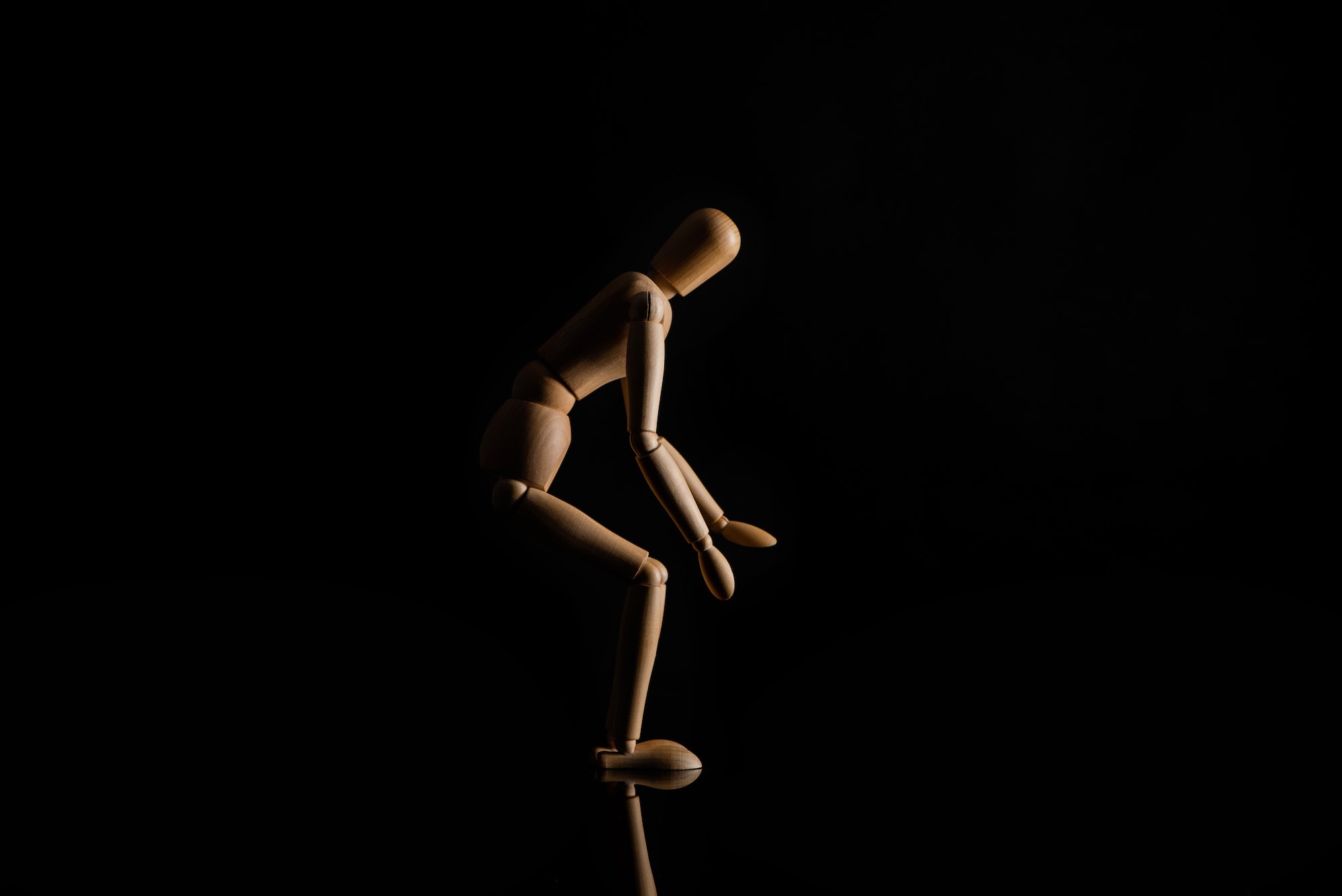 Wooden Doll in Sitting Position on Black Background
