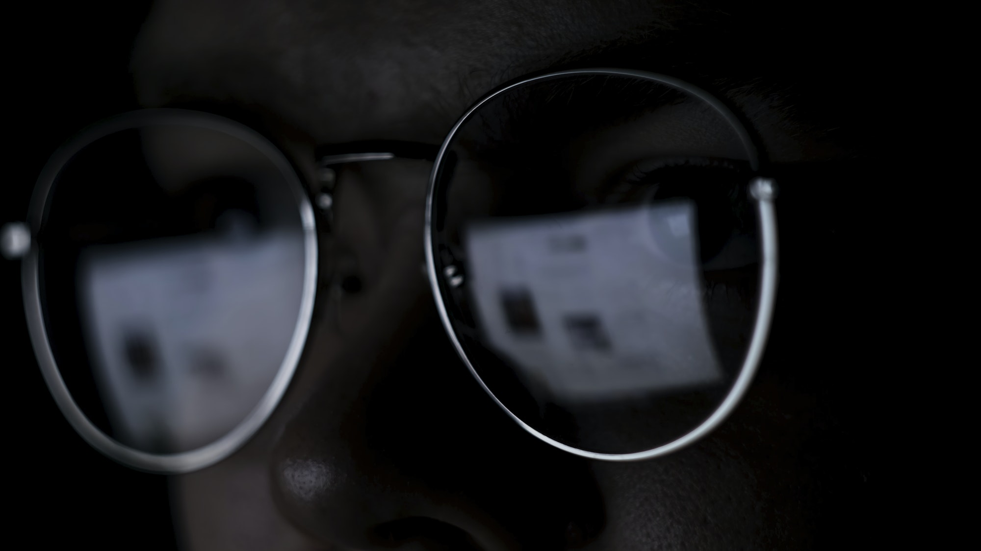 Man works on internet with the reflection of a monitor inside glasses. Concept. Close up of male