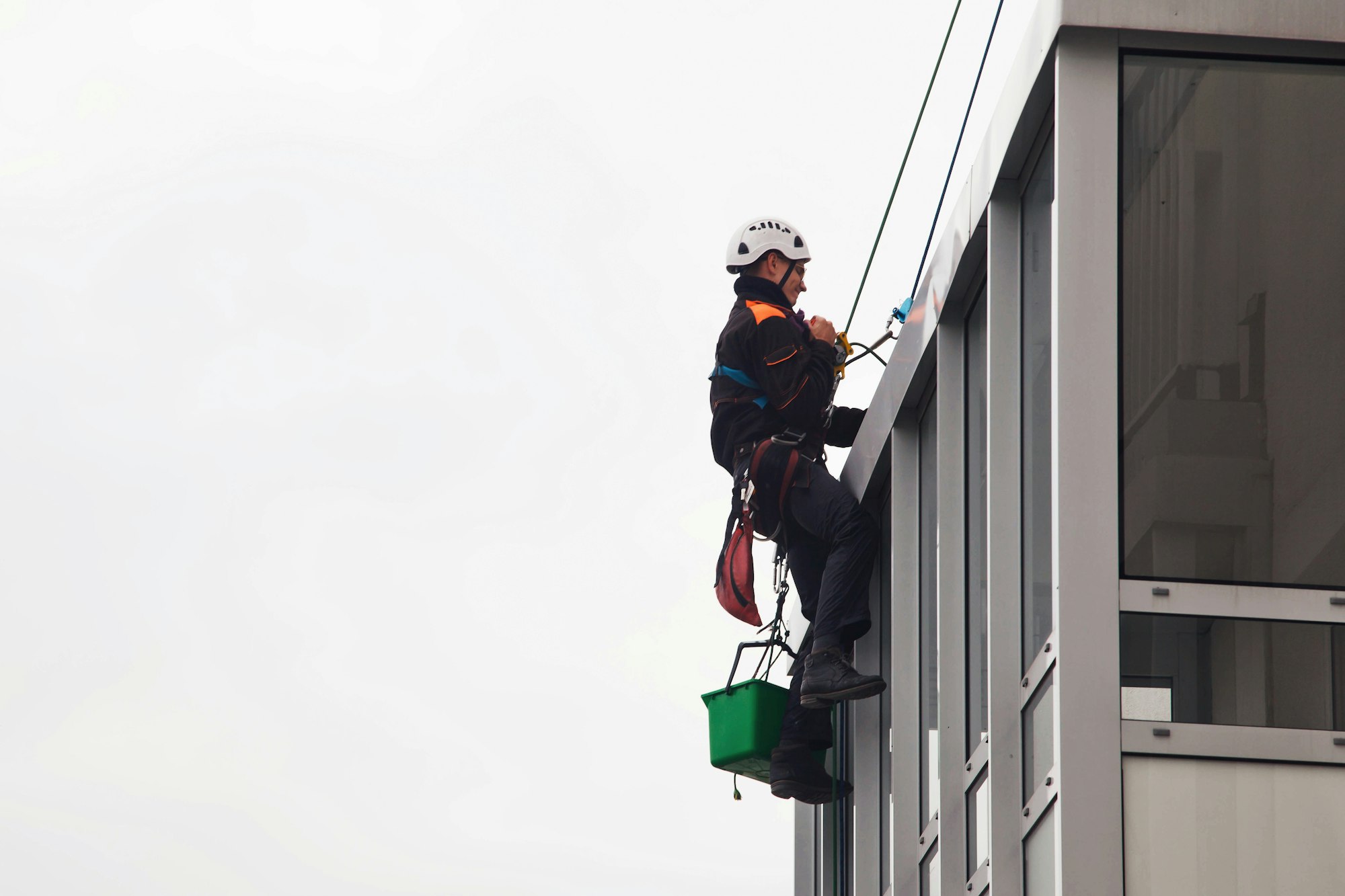 Industrial mountaineering worker hangs over residential building while washing exterior facade