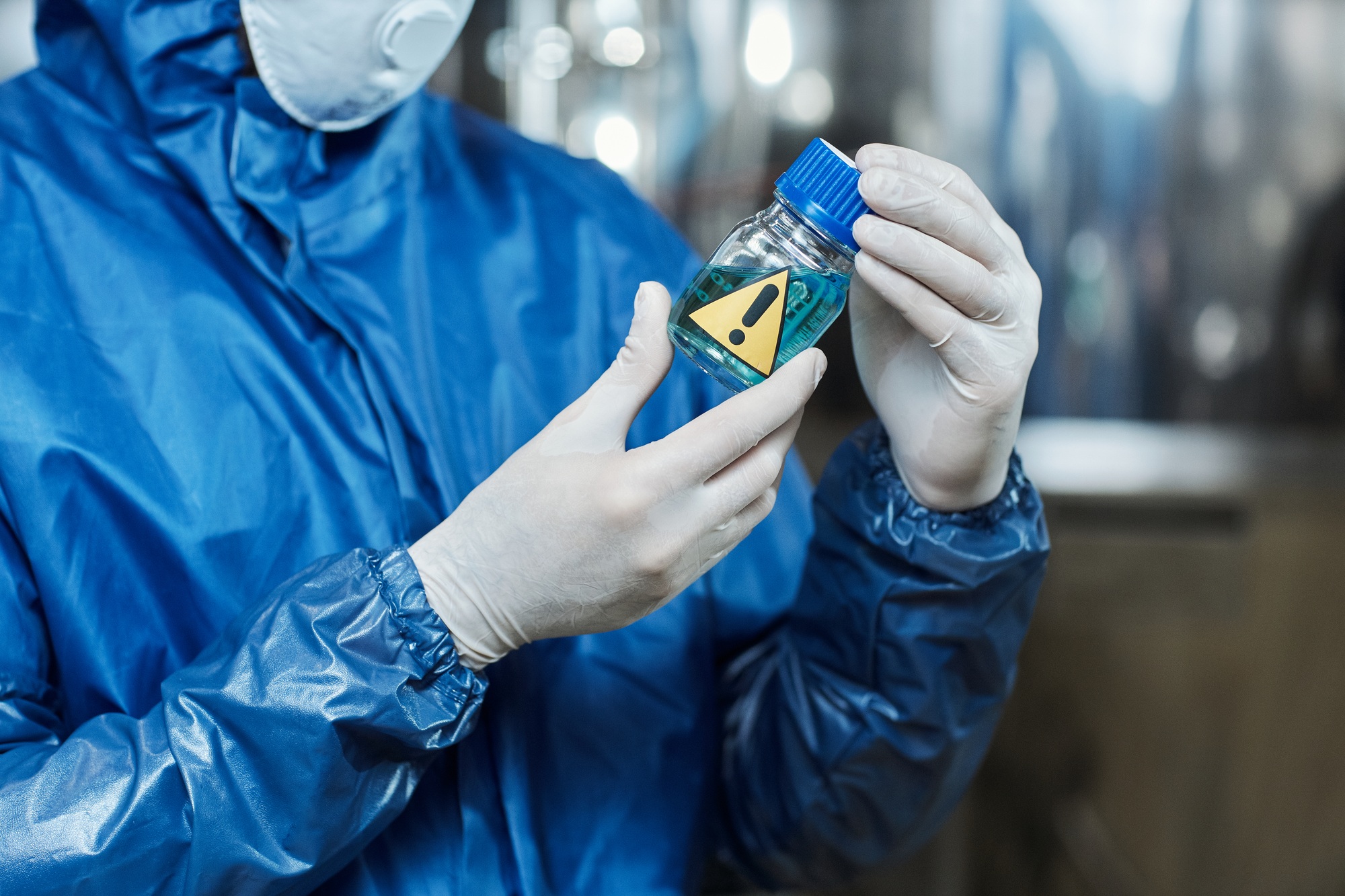Close up of worker holding blue liquid activator at chemical plant