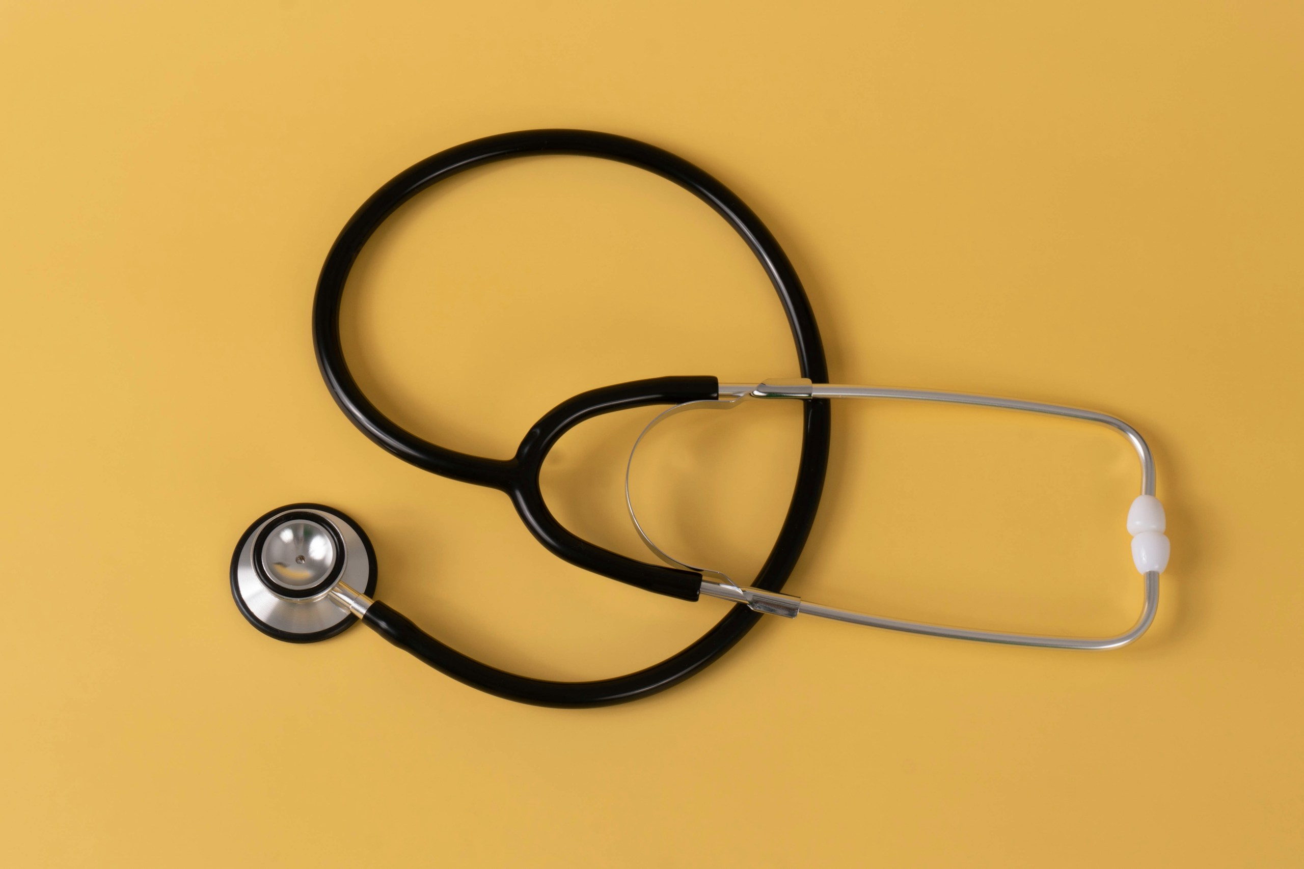 Simple stethoscope on a pastel orange background.